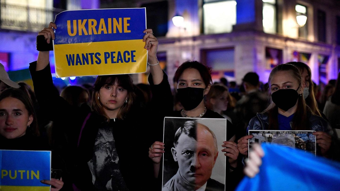 Eine Demonstrantin hält ein Schild mit einer Fotomontage von Adolf Hitler und dem russischen Präsidenten Wladimir Putin hoch