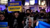 Eine Demonstrantin hält ein Schild mit einer Fotomontage von Adolf Hitler und dem russischen Präsidenten Wladimir Putin hoch