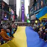 Demonstranten stehen um eine große ukrainische Flagge versammelt auf dem Times Square