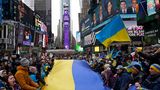 Demonstranten stehen um eine große ukrainische Flagge versammelt auf dem Times Square