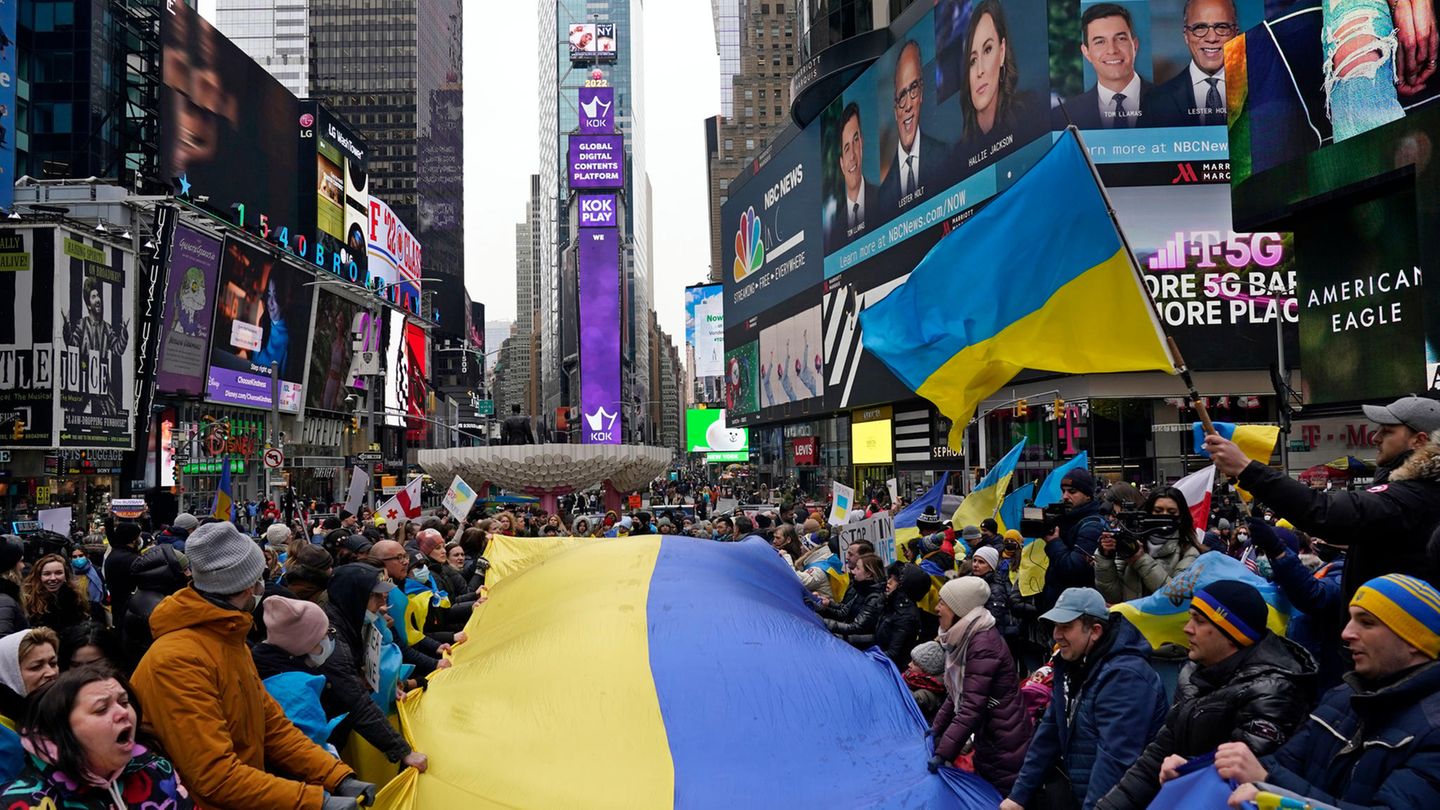 Demonstranten stehen um eine große ukrainische Flagge versammelt auf dem Times Square