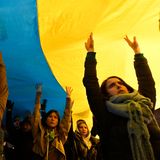 Menschen nehmen vor der russischen Botschaft mit einer riesigen ukrainischen Fahne an einer Demonstration teil