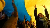 Menschen nehmen vor der russischen Botschaft mit einer riesigen ukrainischen Fahne an einer Demonstration teil
