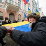Mit einer großen ukrainischen Flagge demonstrieren Menschen vor der russischen Botschaft