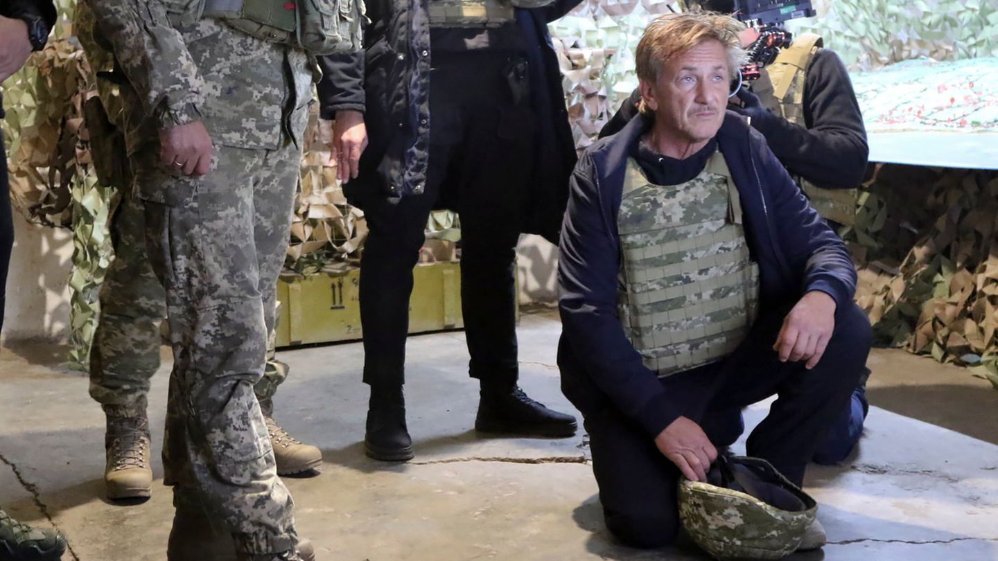 Der Schauspieler Sean Penn sitzt mit einer militärischen Schutzweste auf dem Boden