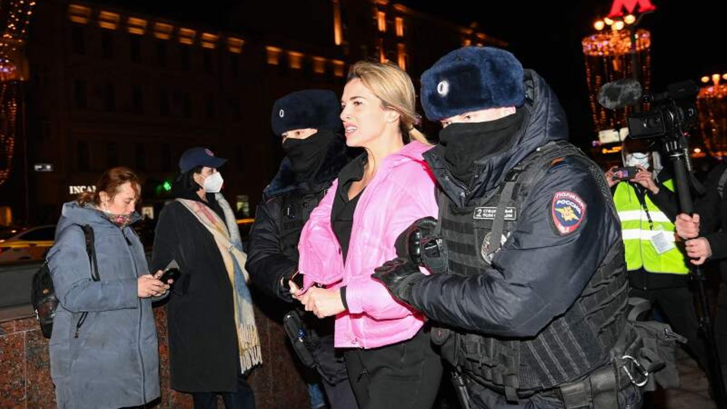 Vermummte Polizeikräfte führen eine Demonstrantin ab