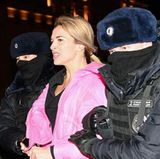 Vermummte Polizeikräfte führen eine Demonstrantin ab