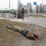 Die Leiche eines getöteten, mutmaßlich russischen Soldatens liegt auf dem Boden, während Soldaten der ukrainischen Armee in eine Unterführung gehen.