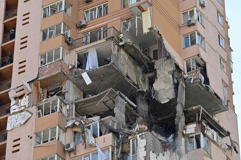 In einem sandfarbenen Hochhaus mit Wohnungen klafft nach einer Explosion ein Loch, durch das zerstörte Betonteile zu sehen sind