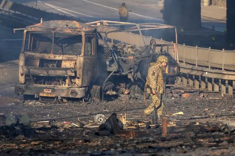 Ukraine, Kiew: Ein ukrainischer Soldat geht an den Trümmern eines ausgebrannten Militärlastwagens vorbei