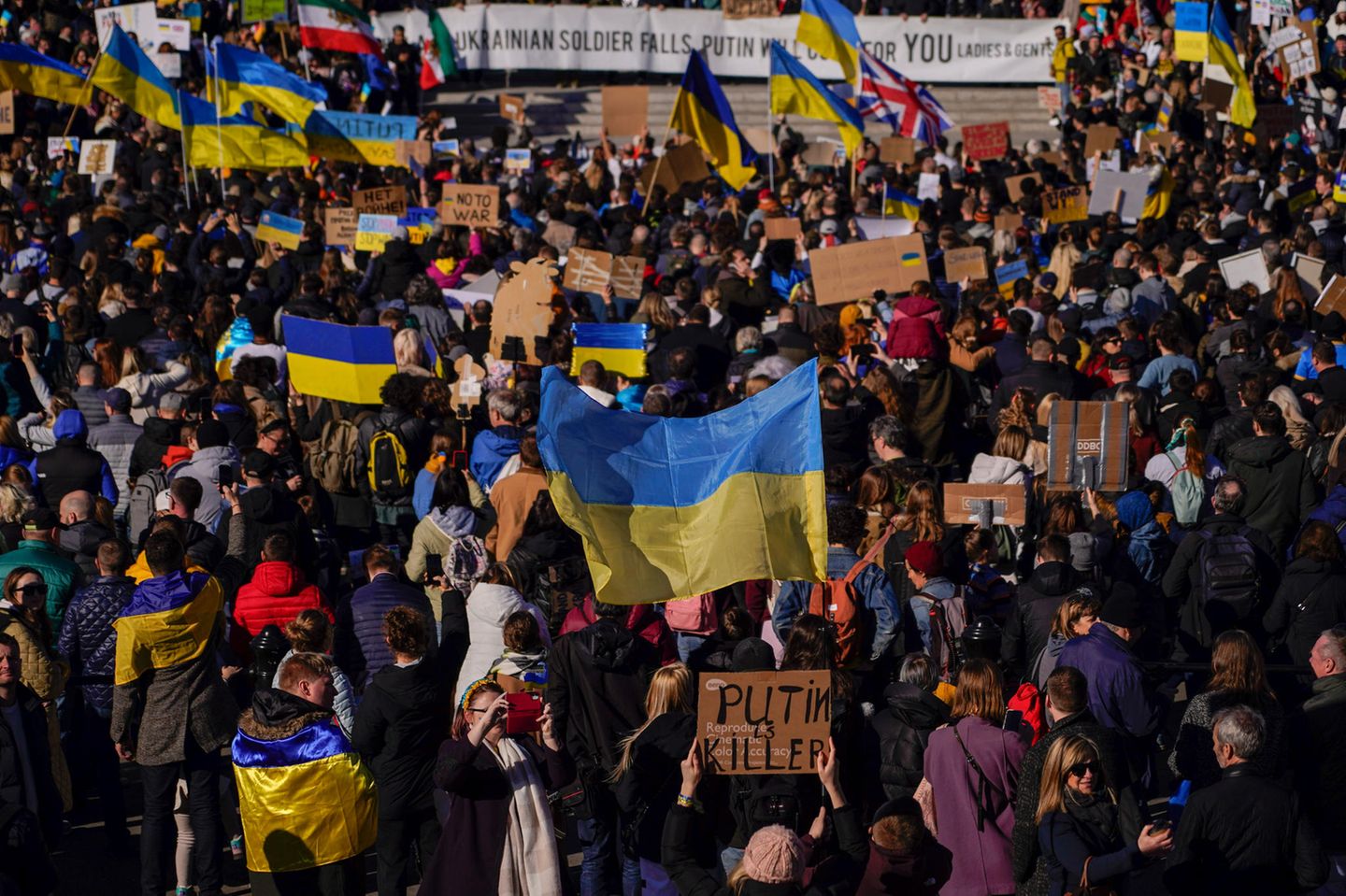 Auf dem Trafalgar Square in London halten Menschen ukrainische Flaggen hoch, und demonstrieren damit gegen den russischen Überfall.