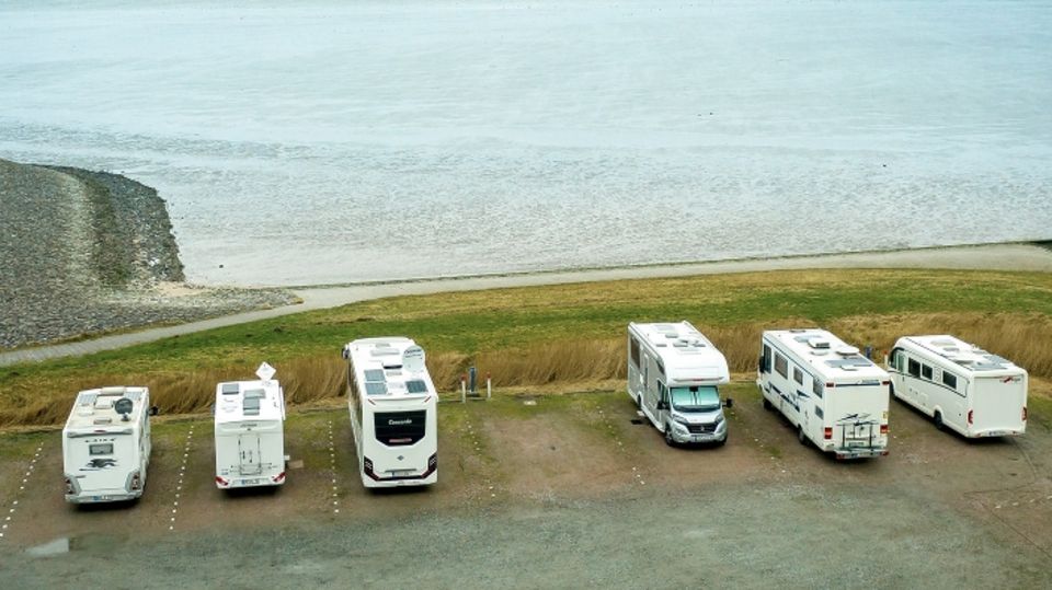 Wohnmobile stehen auf einem Parkplatz in Neuharlingersiel an der Nordseeküste