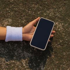 Ein Smartphone in der Hand einer am Boden liegenden Frau