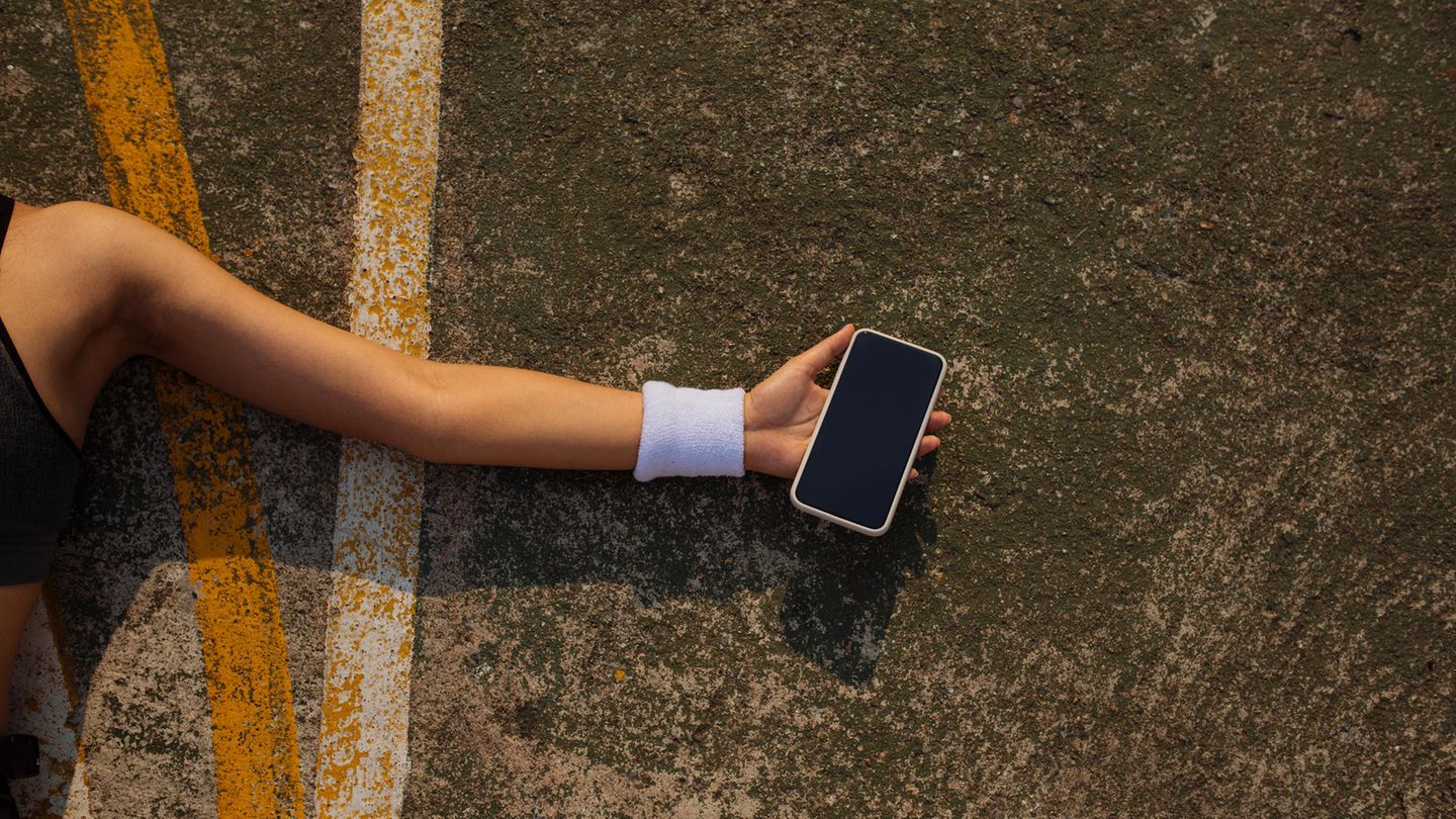 Ein Smartphone in der Hand einer am Boden liegenden Frau