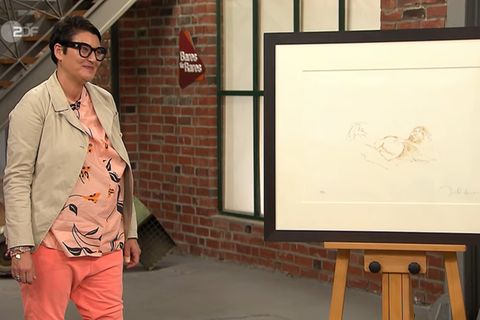 Petra Schindler steht im Studio von Bares für Rares neben der Lithografie