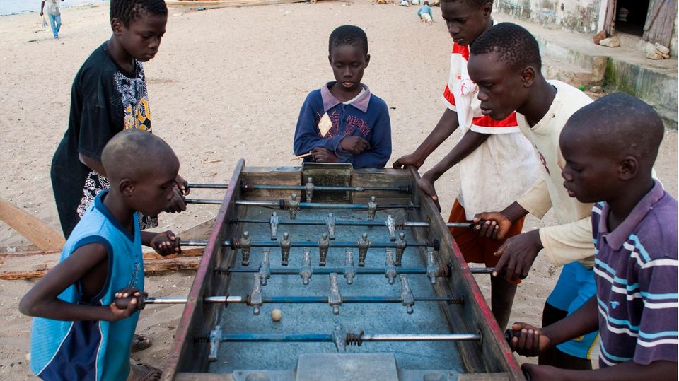 Kinder in Senegal stehen um einen Tischkicker