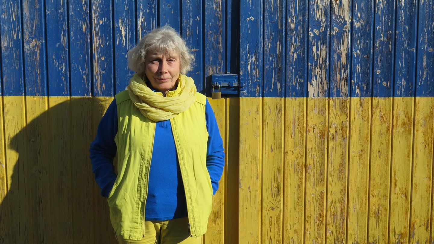 Iryna Denys in blau-gelben Klamotten vor einer blau-gelben Wand