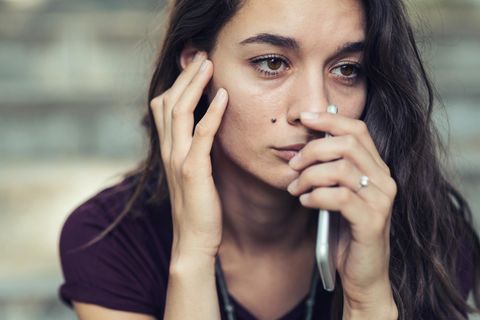 Frau guckt verzweifelt und hält sich ein Handy ans Gesicht