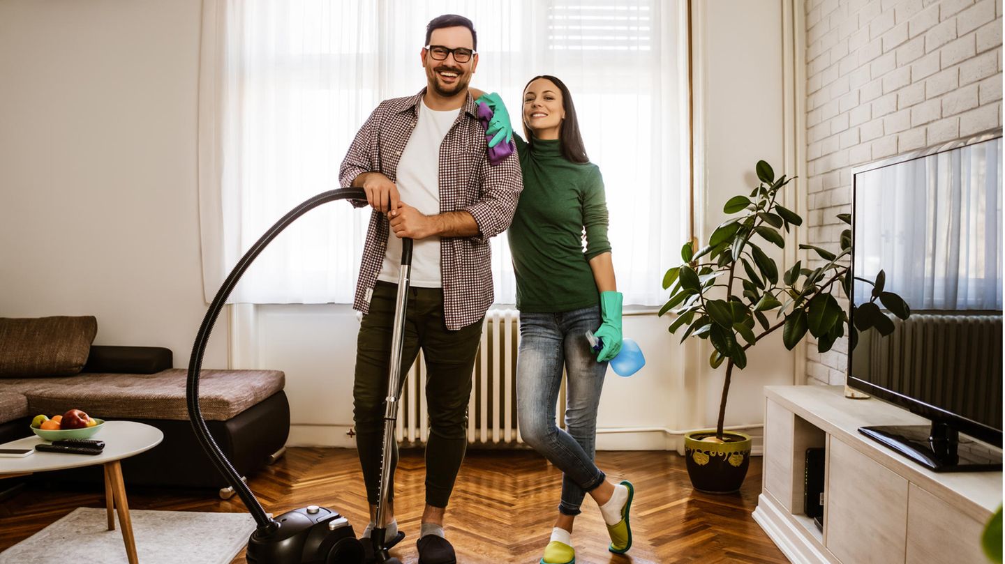 Ein junges Paar putzt gemeinsam das Wohnzimmer