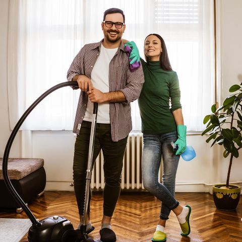 Ein junges Paar putzt gemeinsam das Wohnzimmer