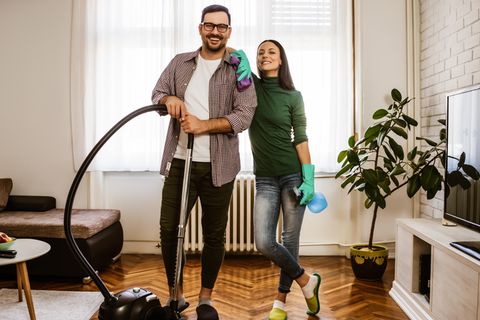 Ein junges Paar putzt gemeinsam das Wohnzimmer