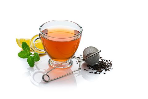 Eine Teekanne mit einer Tasse Tee und einem Teesieb