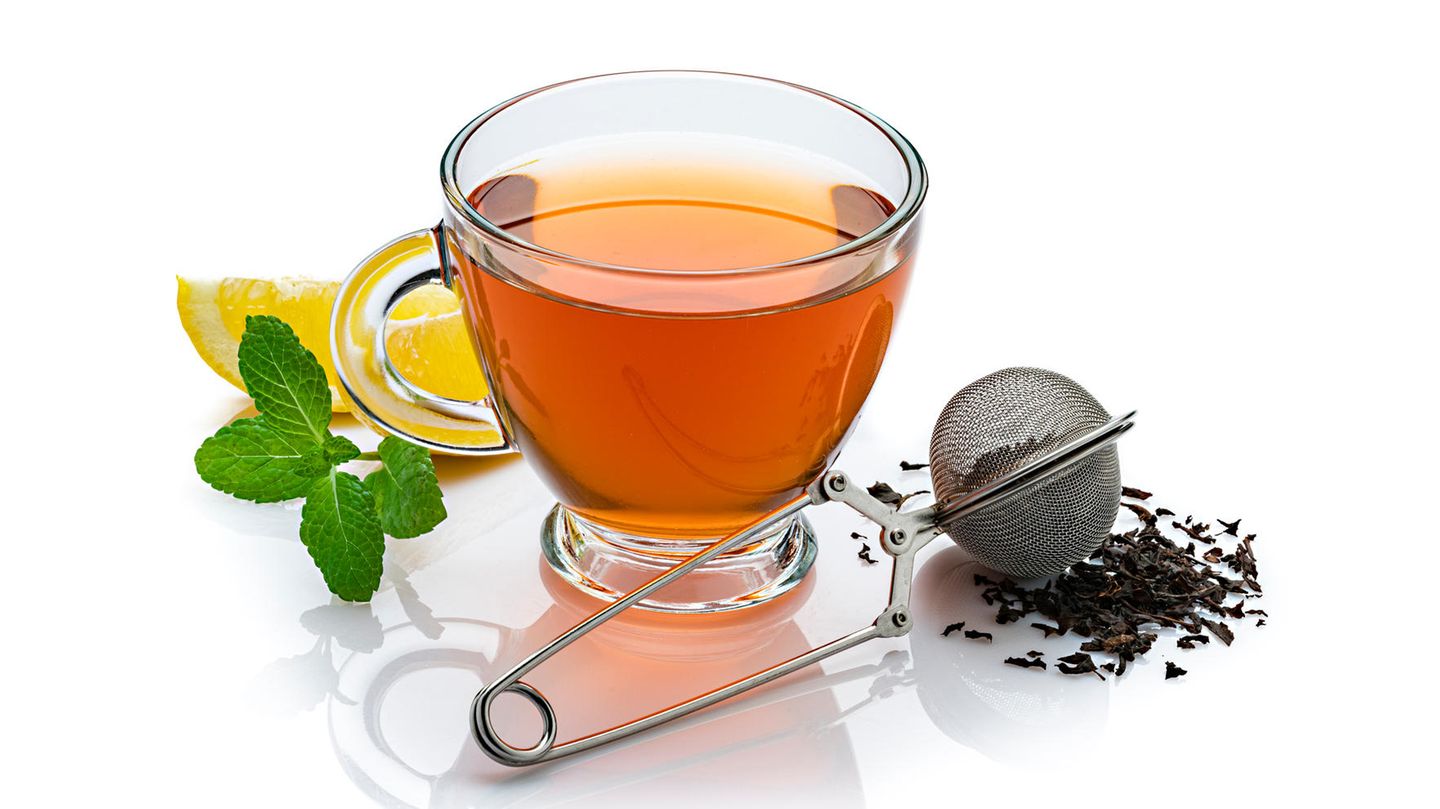 Eine Teekanne mit einer Tasse Tee und einem Teesieb