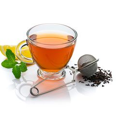 Eine Teekanne mit einer Tasse Tee und einem Teesieb