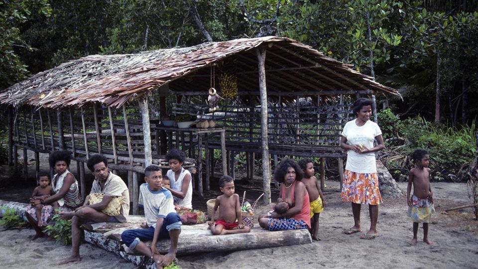Einwohner Papua-Neuguineas vor einem Haus am Strand