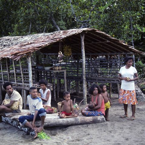 Einwohner Papua-Neuguineas vor einem Haus am Strand