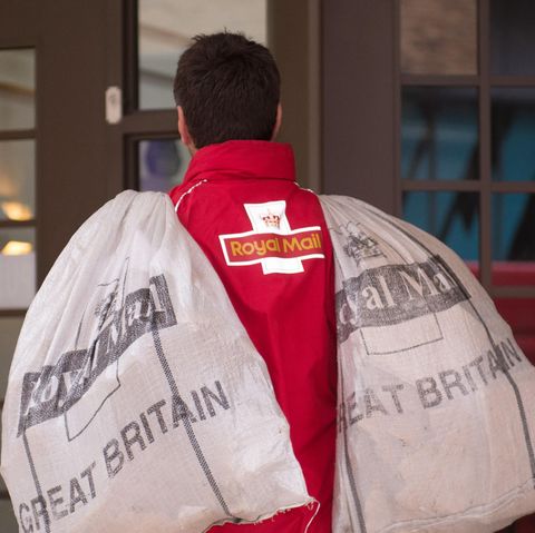 Ein Postbote trägt zwei Säcke mit der Aufschrift "Royal Mail"
