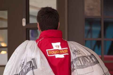 Ein Postbote trägt zwei Säcke mit der Aufschrift "Royal Mail"