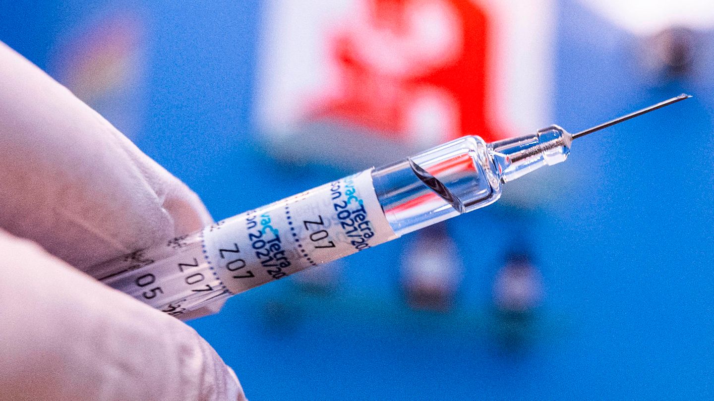 Apotheker  hält eine Spritze vor dem Apotheke-Logo