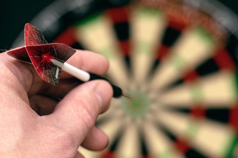 Dart Training: Hand mit Dartpfeil zielt aufs Board