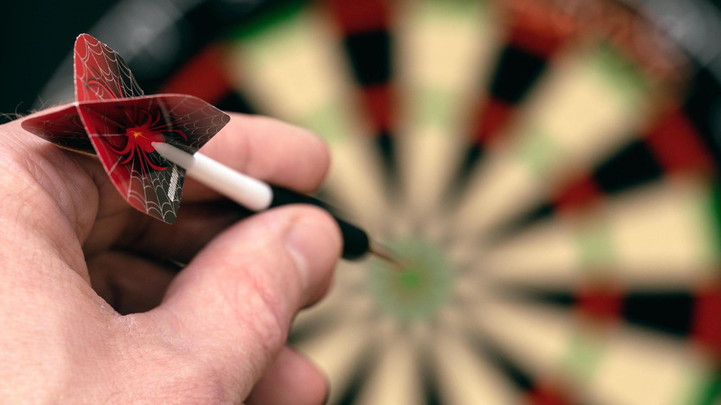Dart Training: Hand mit Dartpfeil zielt aufs Board