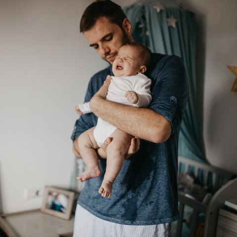 Vater versucht Baby mit Bauchschmerzen zu beruhigen