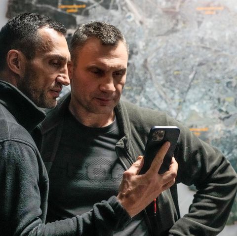 Wladimir und Vitali Klitschko schauen auf ein Handy