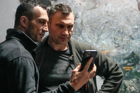 Wladimir und Vitali Klitschko schauen auf ein Handy