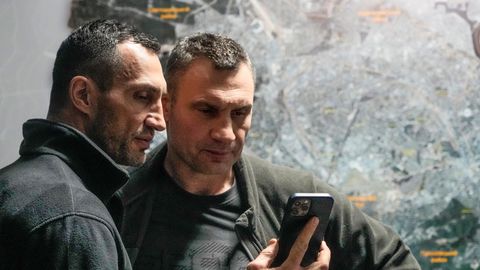 Wladimir und Vitali Klitschko schauen auf ein Handy