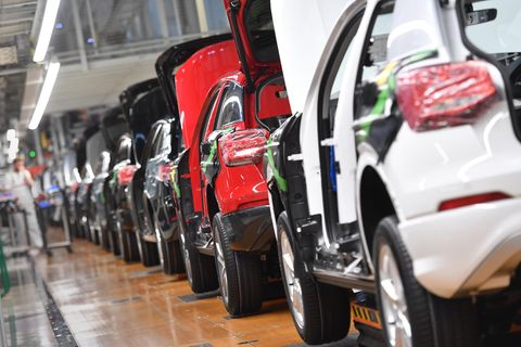 Autos stehen hintereinander auf einem Fließband einer Autoproduktion