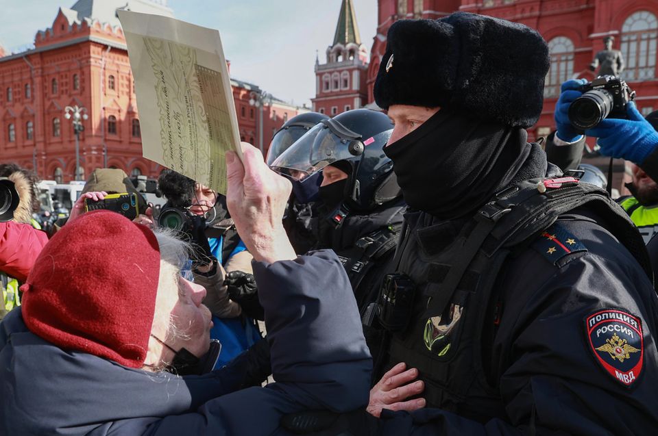 Eine alte Frau stellt sich den vermummten Polizeikräften entgegen