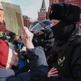 Eine alte Frau stellt sich den vermummten Polizeikräften entgegen