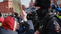 Eine alte Frau stellt sich den vermummten Polizeikräften entgegen