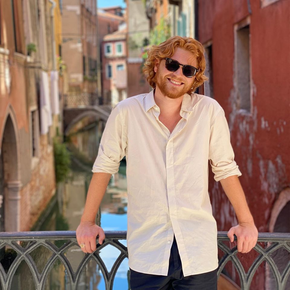 Kai West Schlosser Kai West Schlosser standing on a bridge wearing sunglasses and smiling