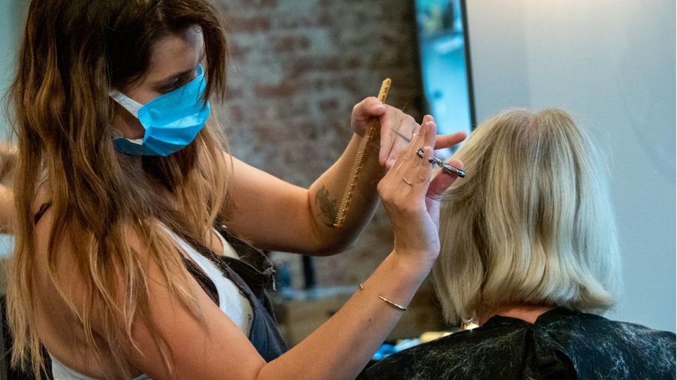 Corona-Pandemie Frauen Glücksatlas Friseurin schneidet Kundin die Haare