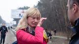 Eine Frau mit blonden Haaren und roter Jacke weint