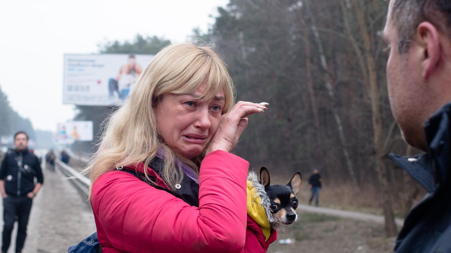 Eine Frau mit blonden Haaren und roter Jacke weint