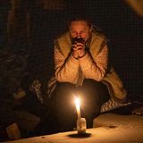 Eine Frau sitzt im Dunkeln, nur eine Kerze brennt