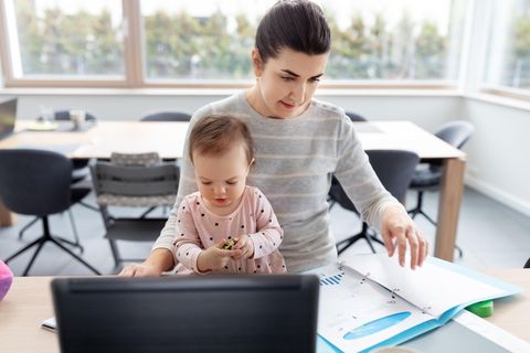 Eine Frau sitzt vor einem Laptop und hält ein Kleinkind auf dem Schoß