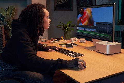 Frau sitzt am Schreibtisch und benutzt einen Mac Studio